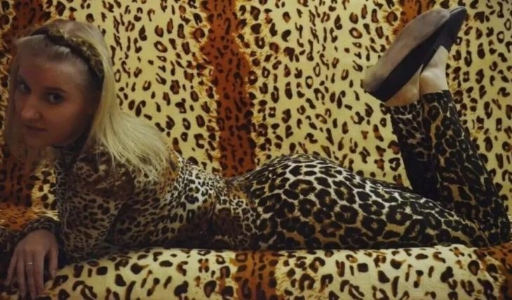 Курящая мамка в кожаных перчатках позирует на леопардовом кресле